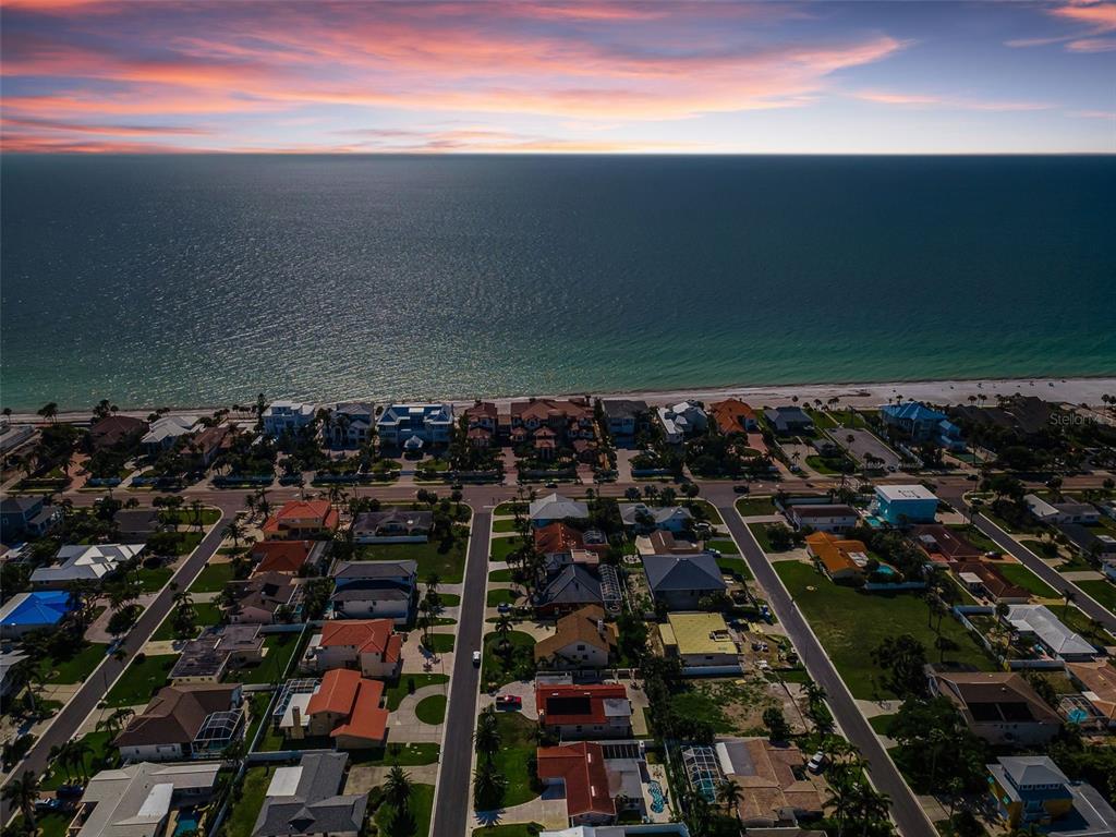 An aerial view shows a coastal neighborhood with houses situated along a sandy beach — 111 17TH STREET, BELLEAIR BEACH, FL
