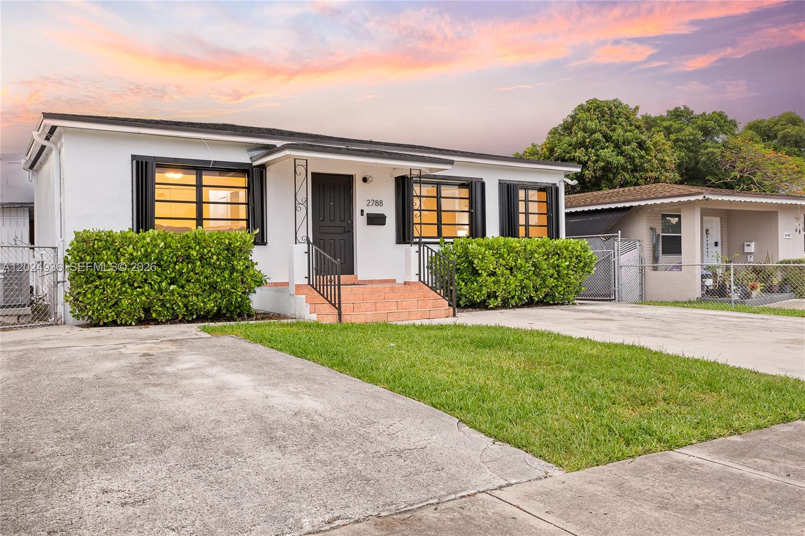 A white single-story house features a black front door, tiled steps, and a concrete driveway — 2788 SW 33rd Ct # A, Miami FL 33133, MIAMI, FL
