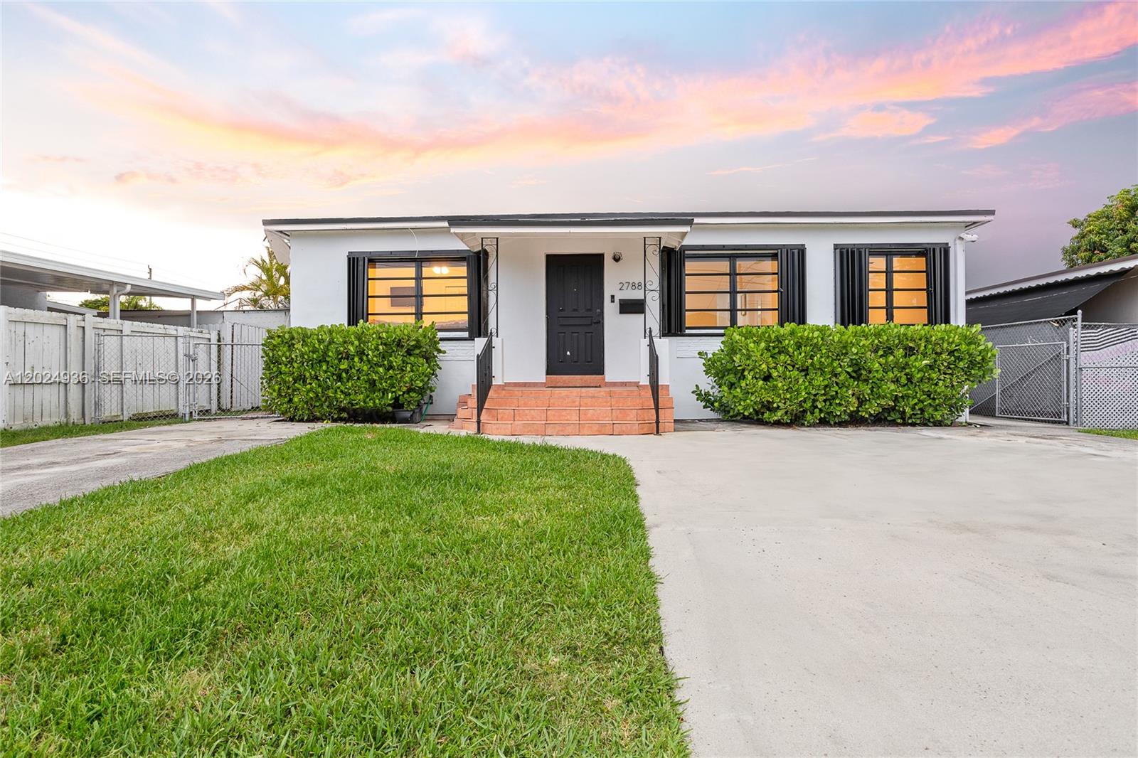 A white single-story house features black window shutters, a dark front door, and concrete driveway — 2788 SW 33rd Ct # A, Miami FL 33133, MIAMI, FL