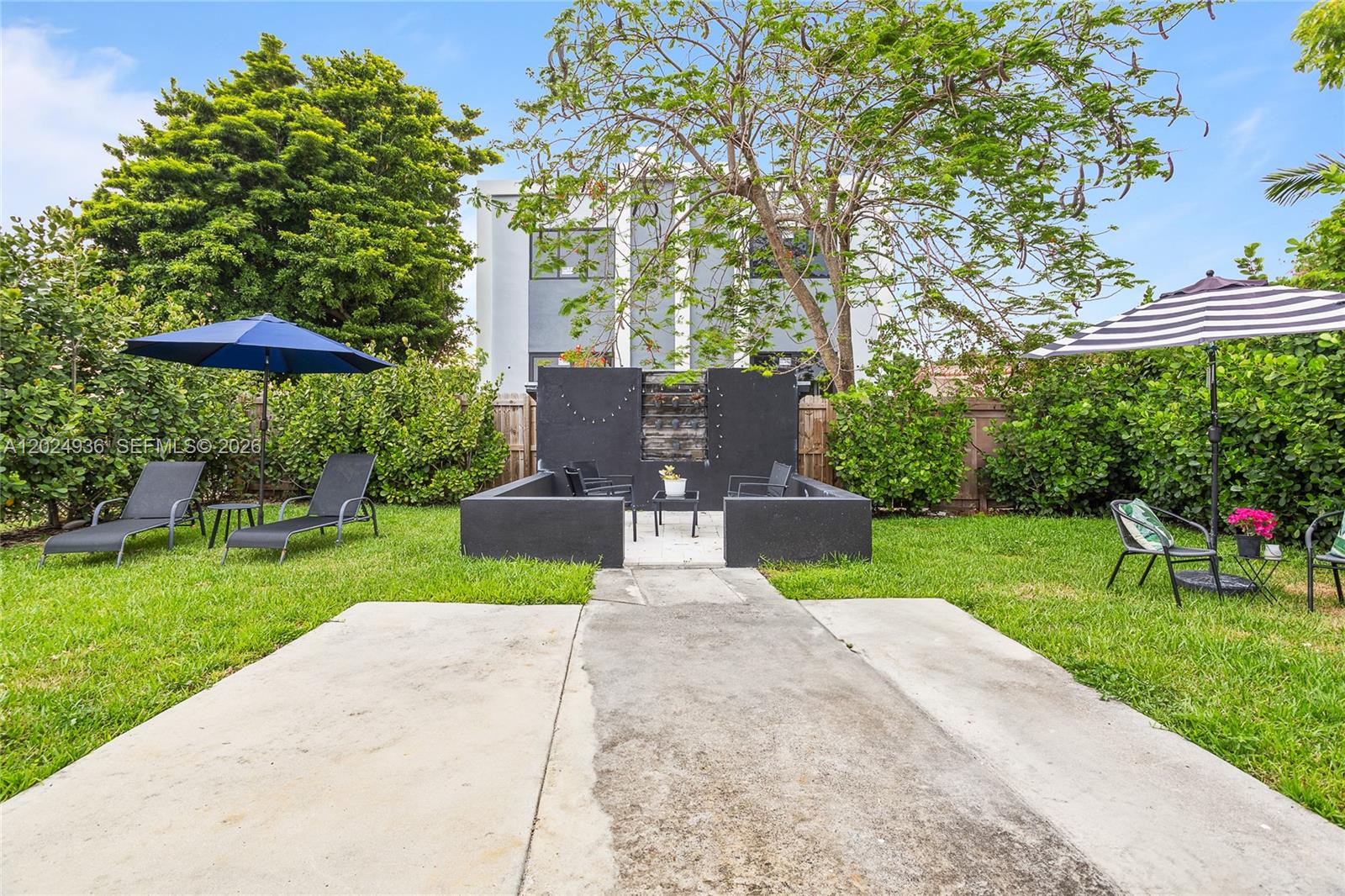 A backyard features a concrete patio, a black water feature, lounge chairs, and patio umbrellas — 2788 SW 33rd Ct # A, Miami FL 33133, MIAMI, FL