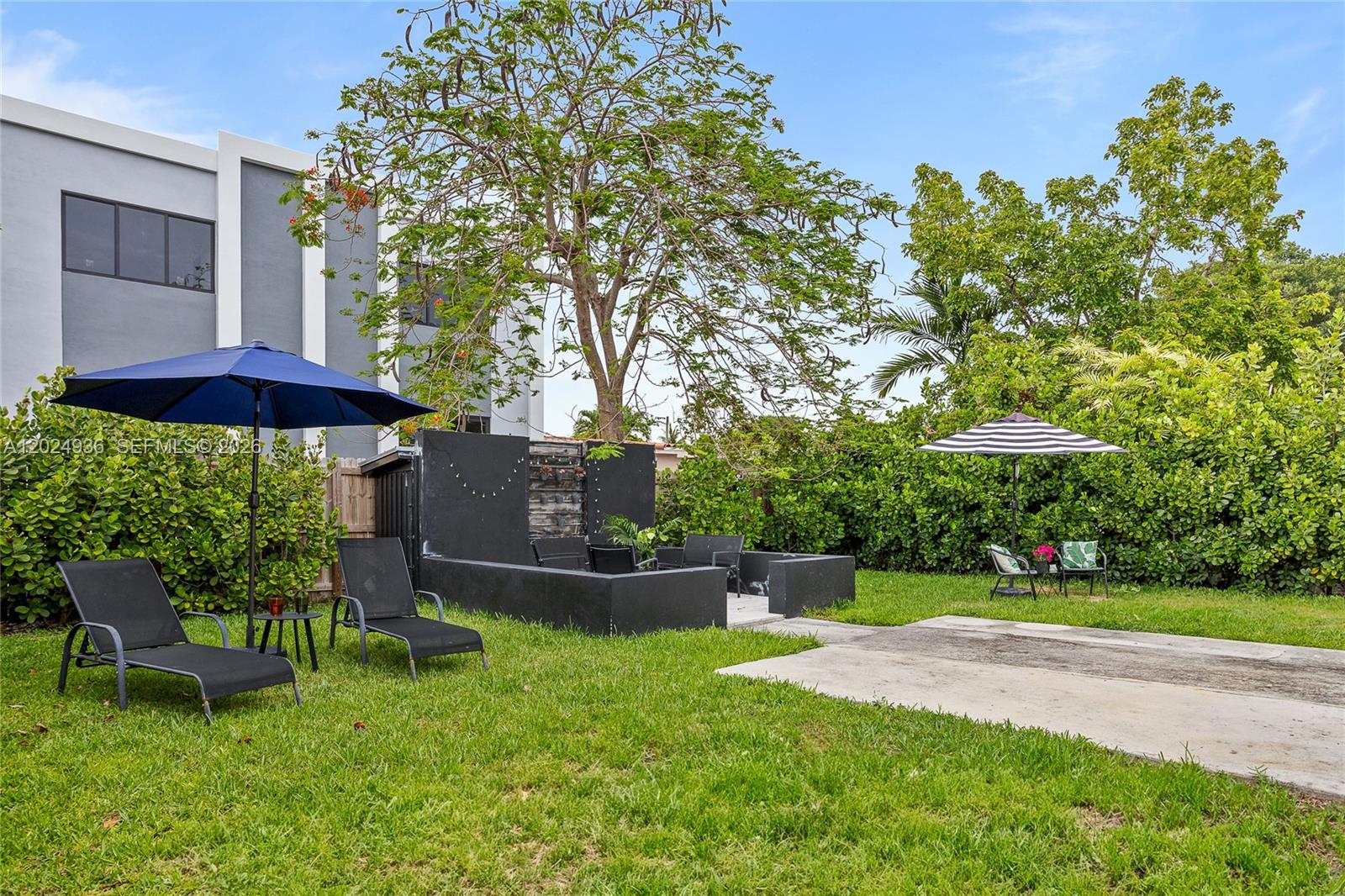 A backyard features a lawn, two patio umbrellas, lounge chairs, and a black stone fountain — 2788 SW 33rd Ct # A, Miami FL 33133, MIAMI, FL
