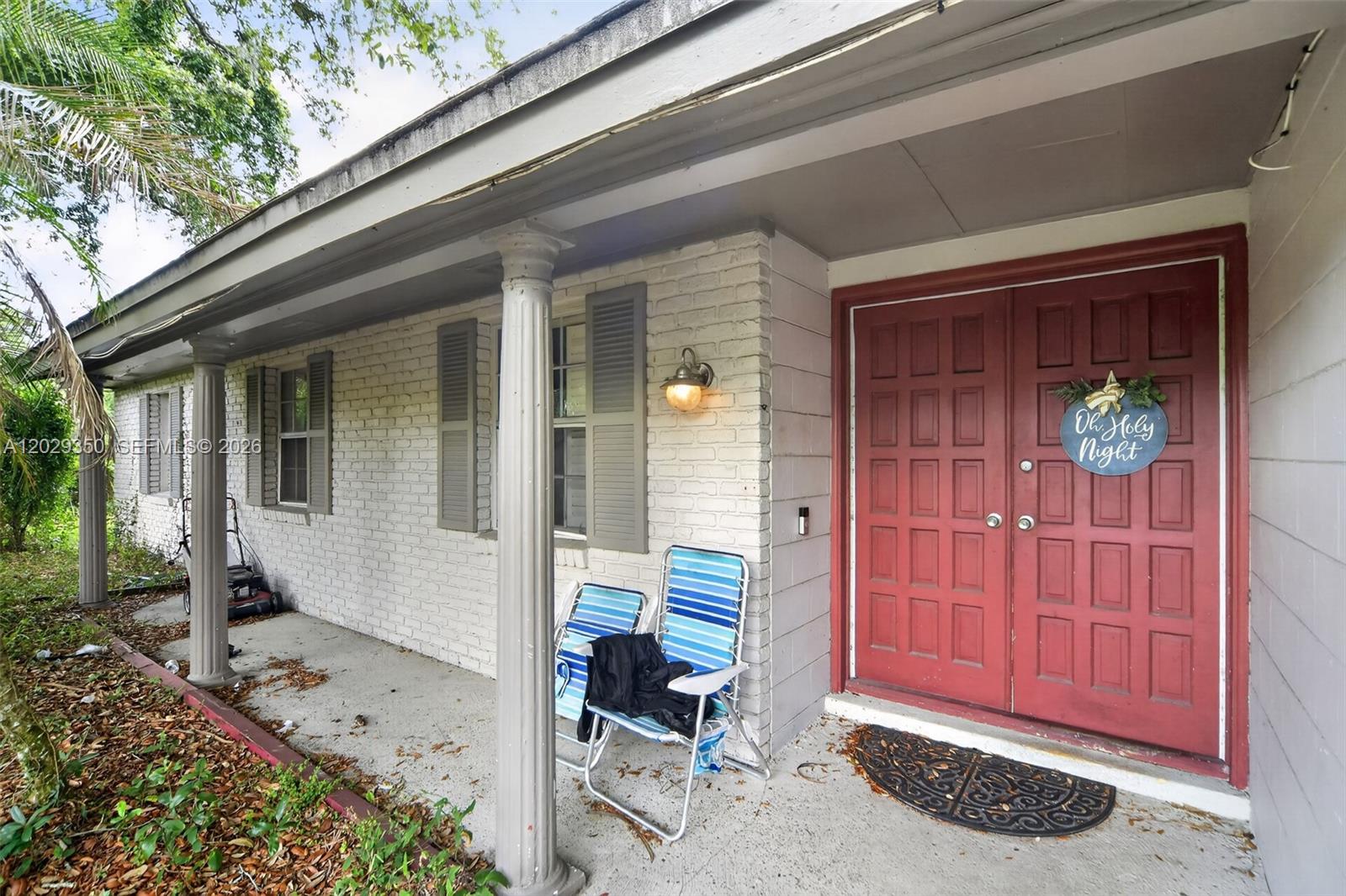 A covered porch with white brick walls, columns, and a red double front door — 570 N HART BLVD, Orlando FL 32818, ORLANDO, FL