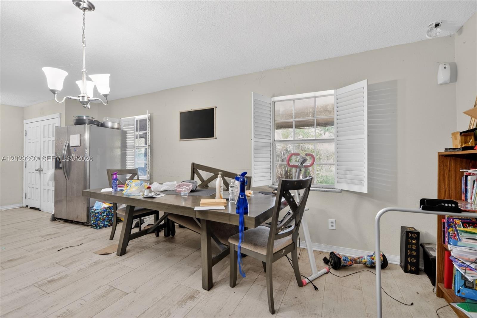A dining area features a wooden table, chairs, a stainless steel refrigerator, and a window — 570 N HART BLVD, Orlando FL 32818, ORLANDO, FL