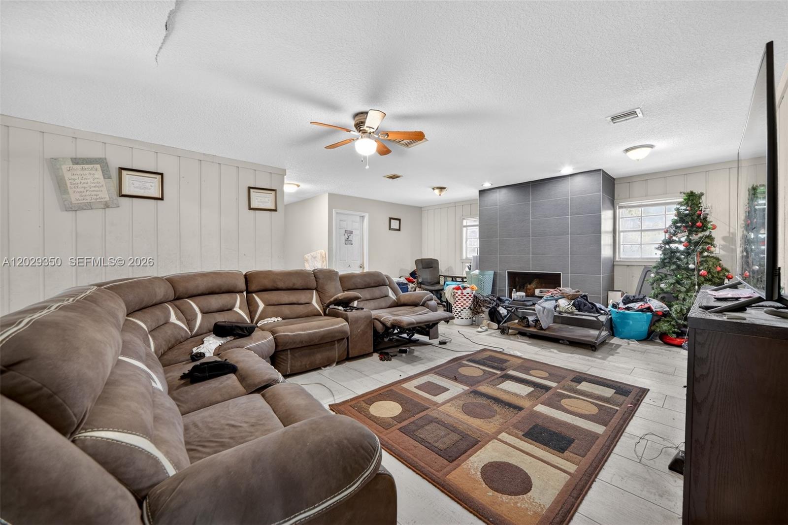 A living room features a large brown sectional sofa, a fireplace with gray tile, and flooring — 570 N HART BLVD, Orlando FL 32818, ORLANDO, FL