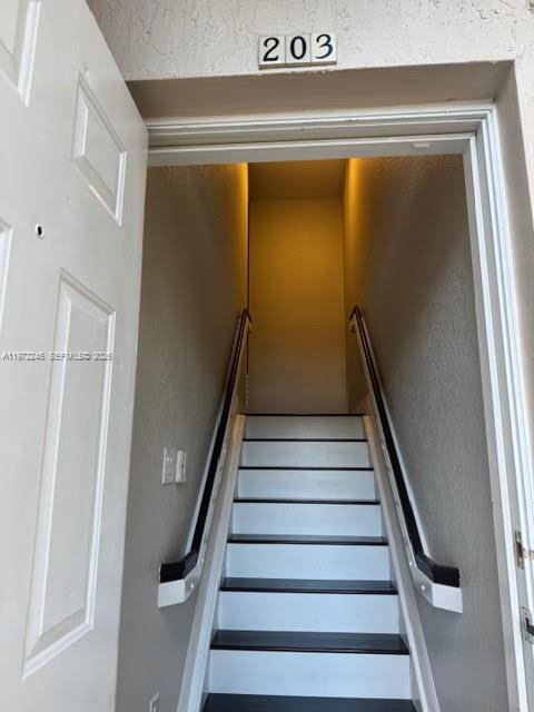 An interior view of a staircase leading upward through a doorway marked with number 203 — 5650 NW 115th Ct # 203, Doral FL 33178, DORAL, FL