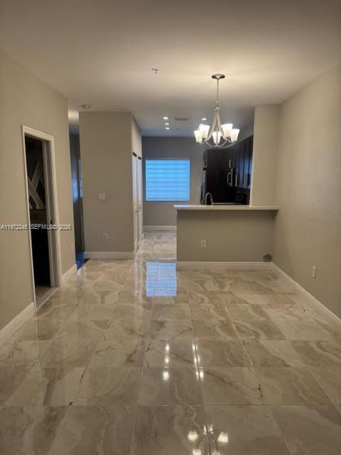 A view of a kitchen with a breakfast bar, chandelier, and polished tile flooring — 5650 NW 115th Ct # 203, Doral FL 33178, DORAL, FL