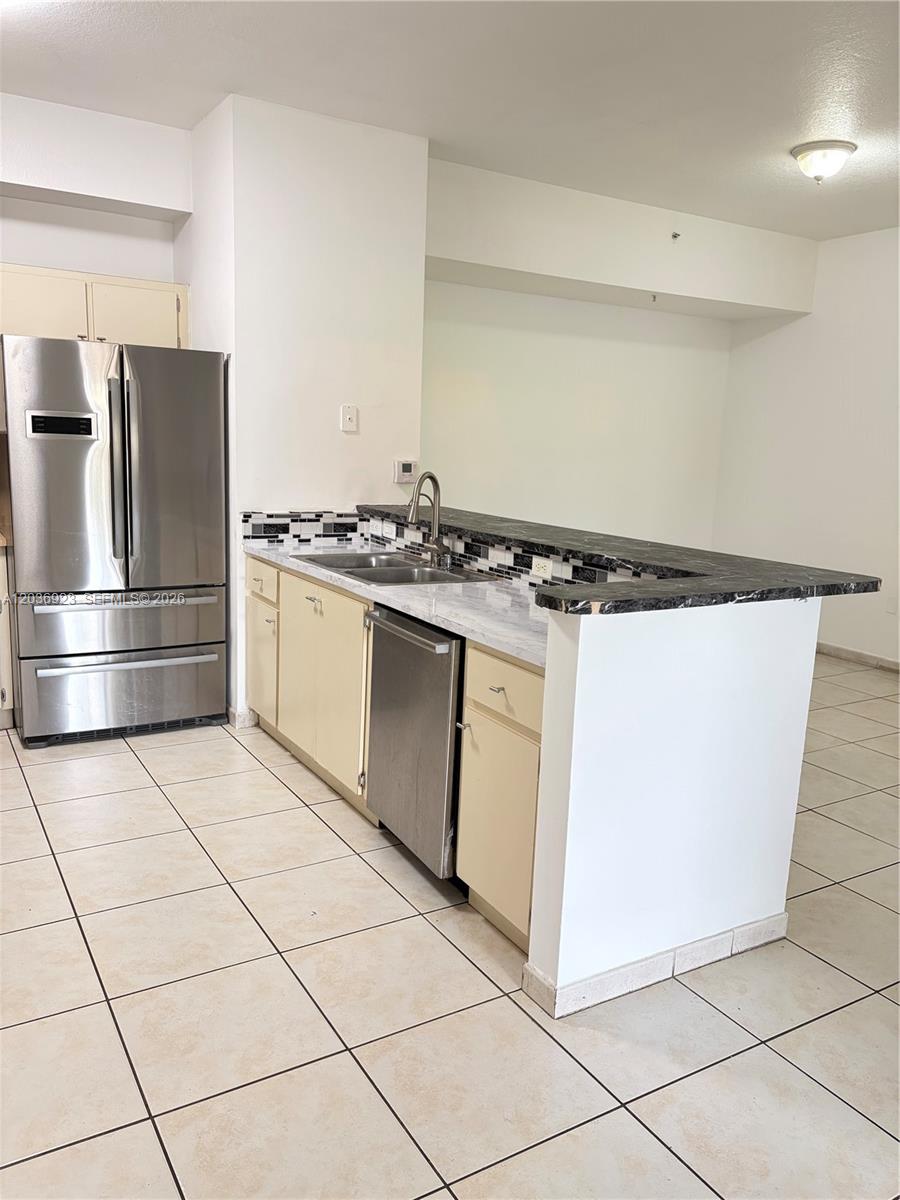 A kitchen features light-colored cabinets, stainless steel appliances, and a dark stone breakfast bar — 7360 NW 114th Ave # 103, Doral FL 33178, DORAL, FL