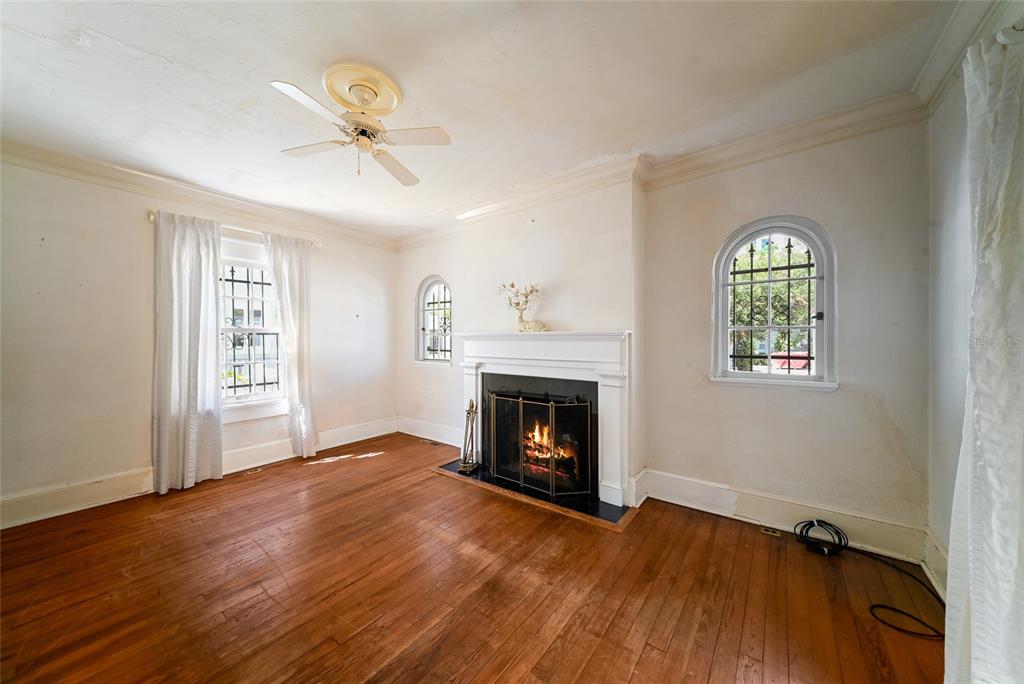 A living room features hardwood floors, a white fireplace, and arched windows with metal grilles — 411 BURNS COURT, SARASOTA, FL