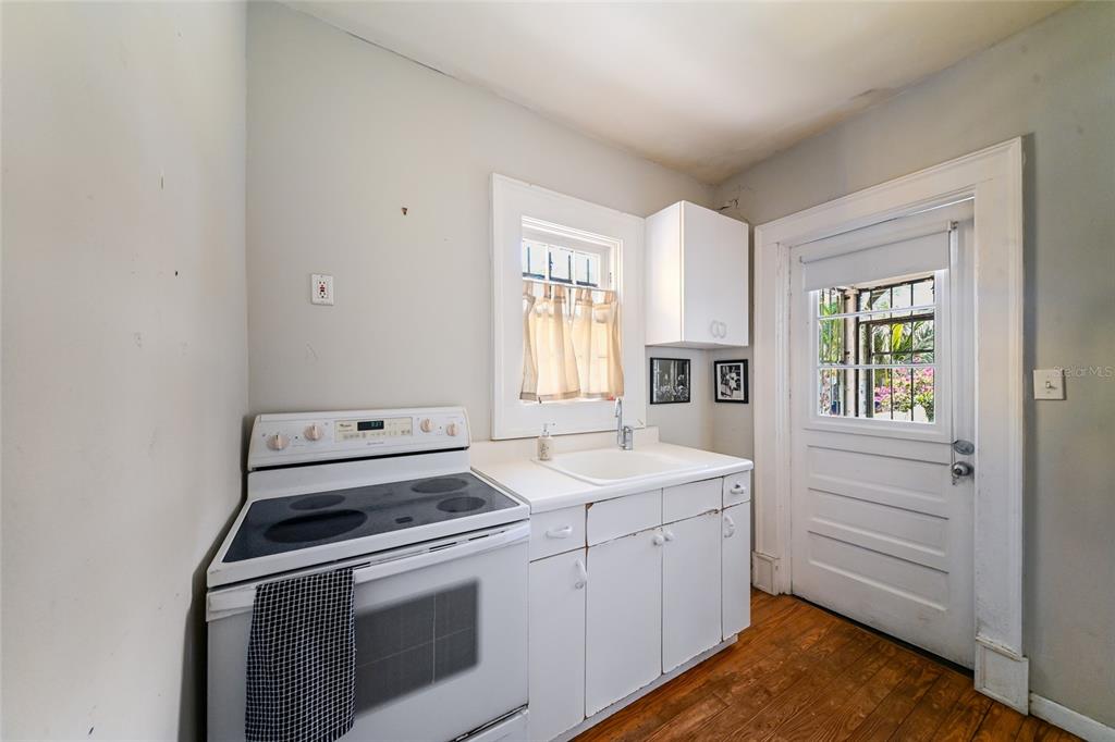 A small kitchen features a white electric stove, a sink, white cabinets, and a back door — 411 BURNS COURT, SARASOTA, FL