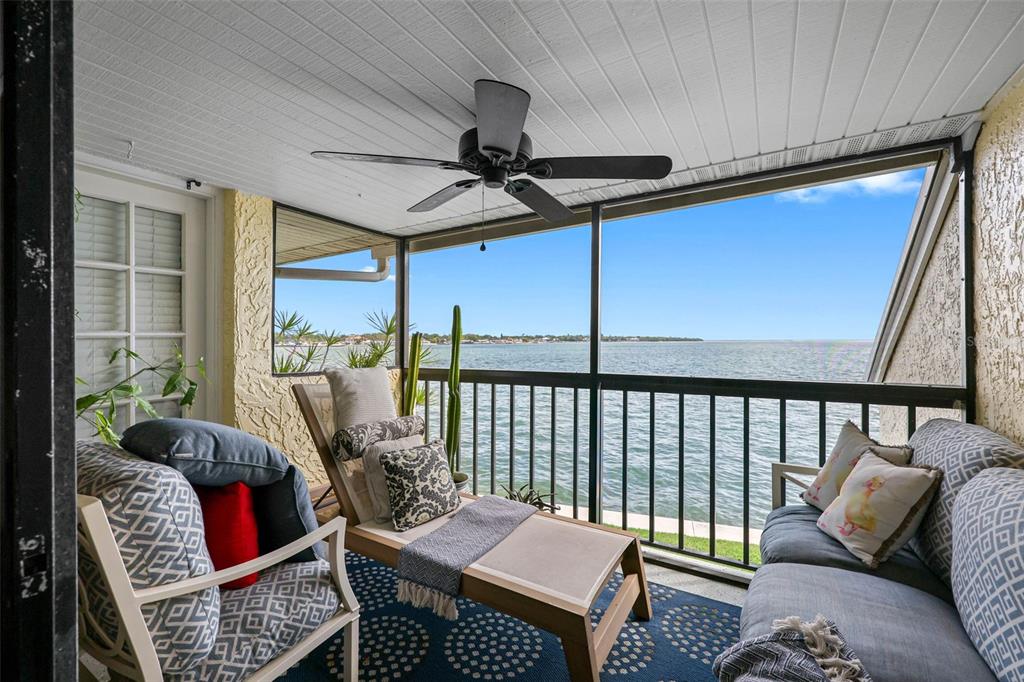 A screened-in balcony features outdoor furniture, a ceiling fan, and a view of the water — 7300 SUNSHINE SKYWAY LANE S UNIT 210, ST PETERSBURG, FL