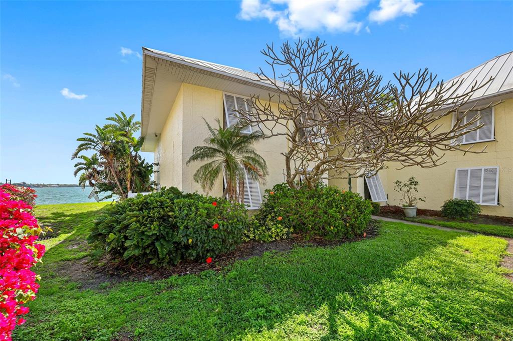 The exterior of a yellow two-story building features white shutters, landscaping, and a waterfront view — 7300 SUNSHINE SKYWAY LANE S UNIT 210, ST PETERSBURG, FL
