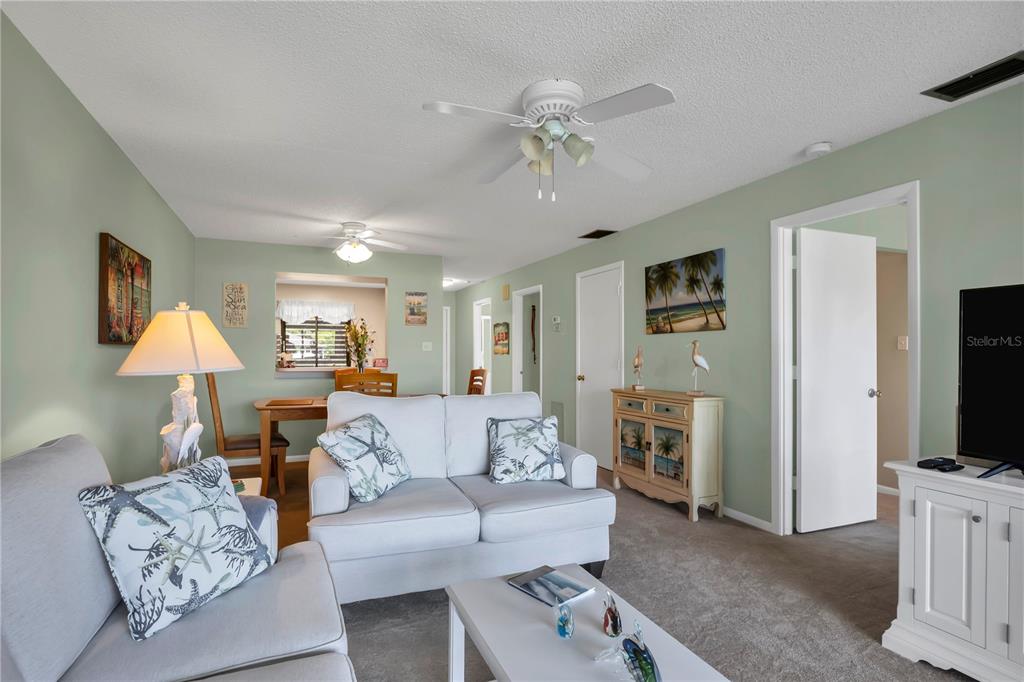 A living room features light green walls, a white sofa, and a ceiling fan — 5205 LAKE VILLAGE DRIVE UNIT 16, SARASOTA, FL