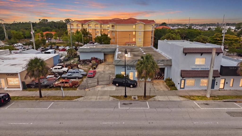 An aerial view shows a commercial street with a tattoo studio, auto shop, and parked cars — 629 E VENICE AVENUE, VENICE, FL