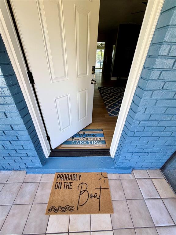 An open white door leads into a home with a blue brick exterior — 1151 CAREFREE COVE DRIVE, WINTER HAVEN, FL