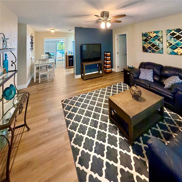 A living room with wood-look flooring, a blue accent wall, and an adjacent dining area — 1151 CAREFREE COVE DRIVE, WINTER HAVEN, FL