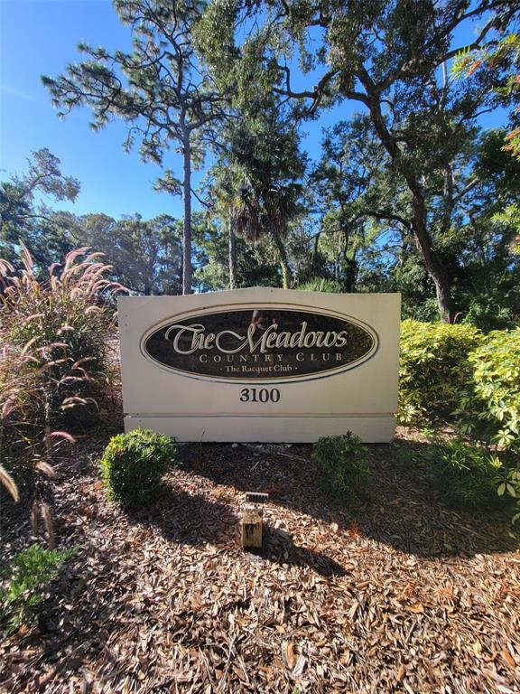 A sign for The Meadows Country Club stands in a landscaped area with trees — 3097 WILLOW GREEN UNIT 32, SARASOTA, FL