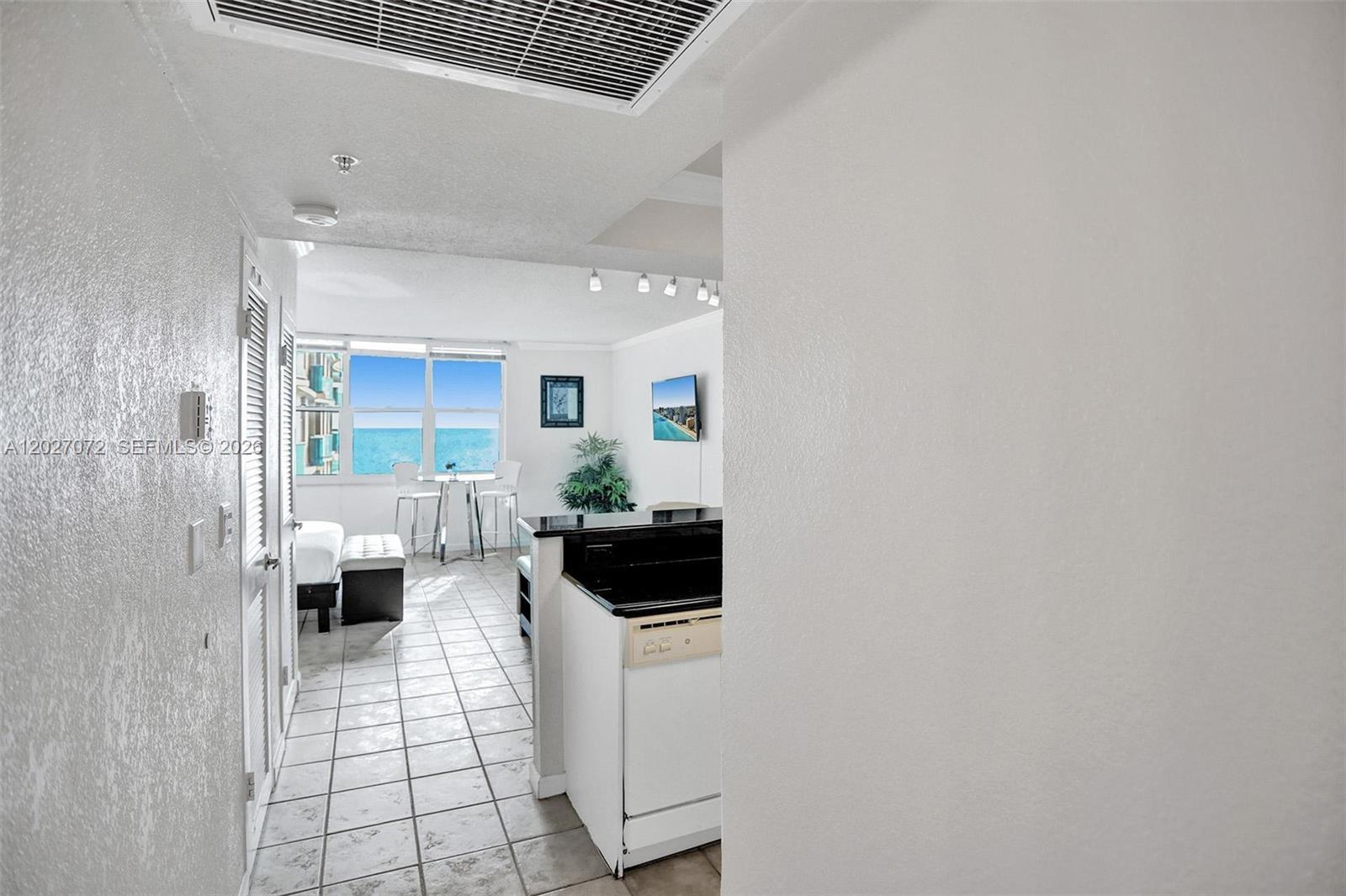 A kitchen with black countertops overlooks a living area with a view of the ocean — 2501 S Ocean Dr, Hollywood FL 33019, HOLLYWOOD, FL