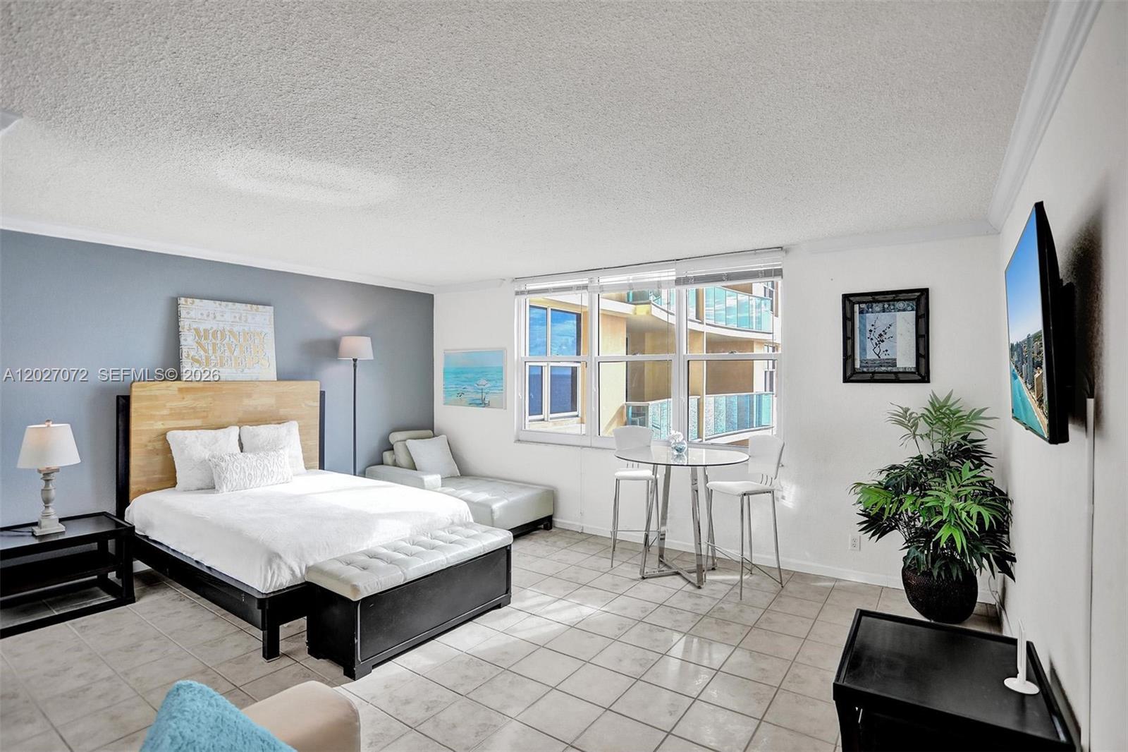 A bedroom features a bed, a small dining table, and a window with balcony views — 2501 S Ocean Dr, Hollywood FL 33019, HOLLYWOOD, FL
