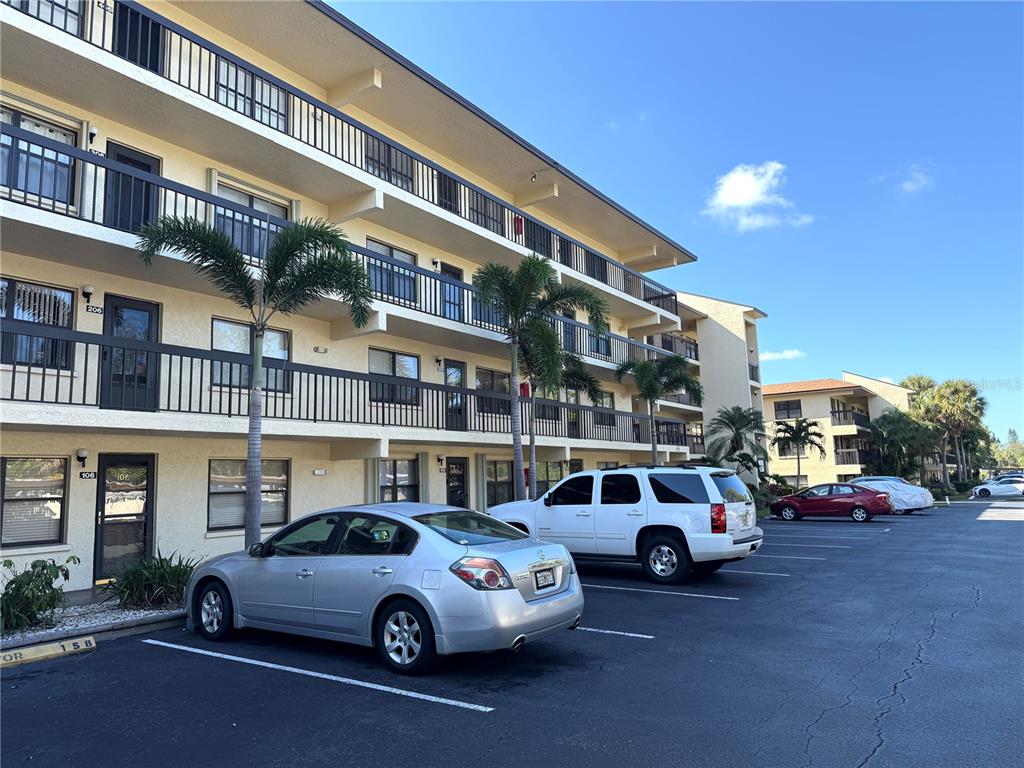 A three-story apartment building with exterior walkways and a parking lot in the foreground — 315 30TH AVENUE W UNIT B305, BRADENTON, FL
