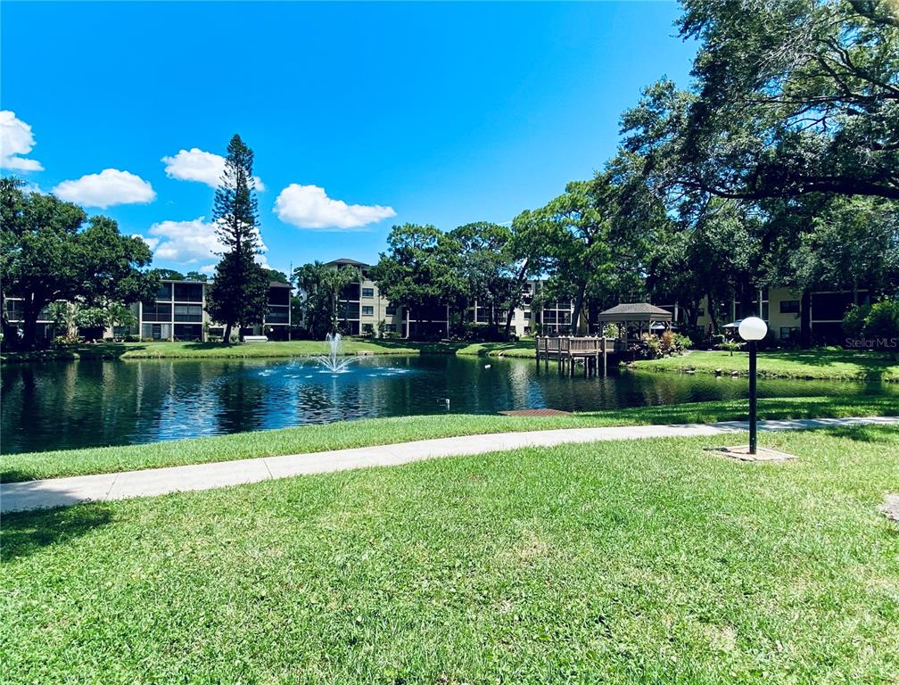 A grassy lawn leads to a pond with a fountain and a wooden gazebo — 315 30TH AVENUE W UNIT B305, BRADENTON, FL