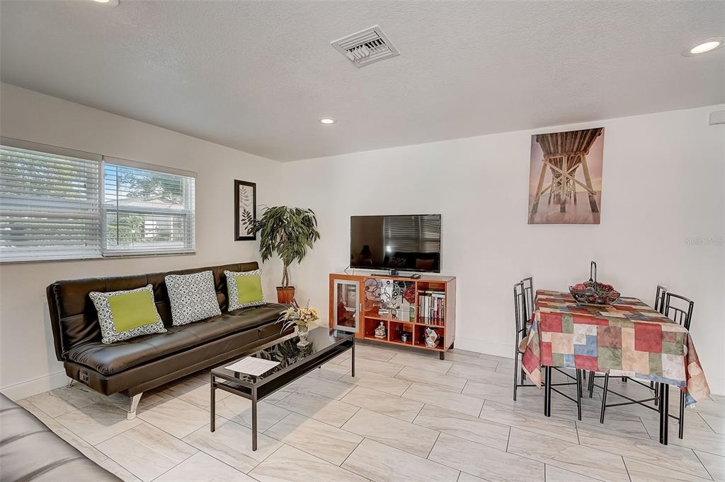 A living and dining room area features a black sofa, television console, and tiled floors — 626 S OSPREY AVENUE, SARASOTA, FL