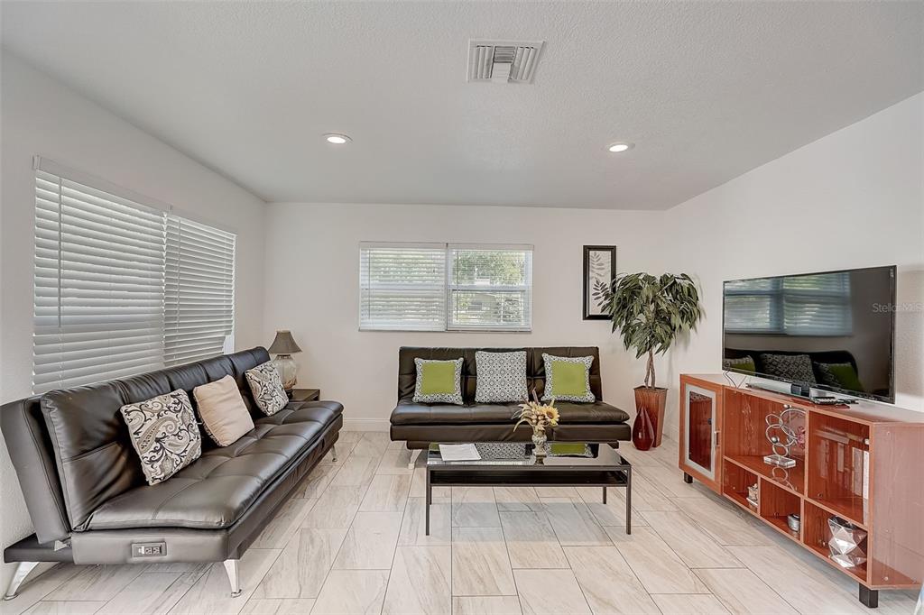A living room features two black futons, a glass coffee table, and a wooden media console — 626 S OSPREY AVENUE, SARASOTA, FL