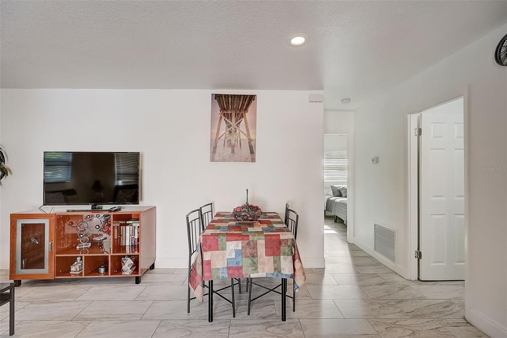 A dining area with a tiled floor, a patterned tablecloth, and a wall-mounted television — 626 S OSPREY AVENUE, SARASOTA, FL