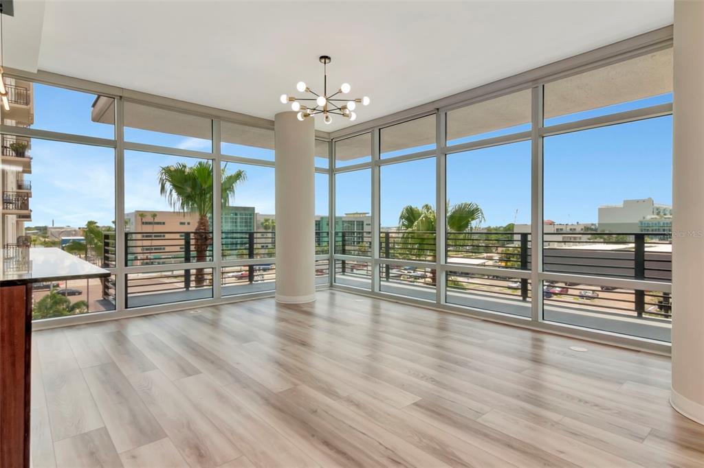 A bright, empty room features floor-to-ceiling windows, light wood flooring, and a modern chandelier — 1208 E KENNEDY BOULEVARD UNIT 419, TAMPA, FL