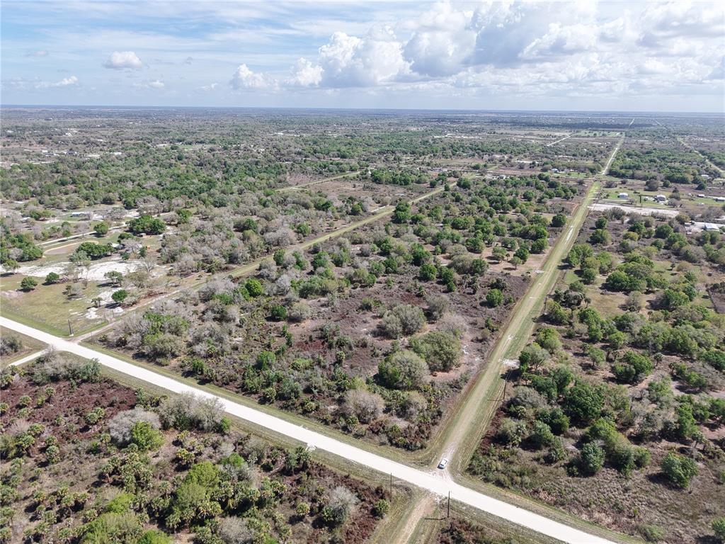 An aerial view shows a rural, undeveloped plot of land intersected by two dirt roads — 20755 NW 262ND STREET, OKEECHOBEE, FL