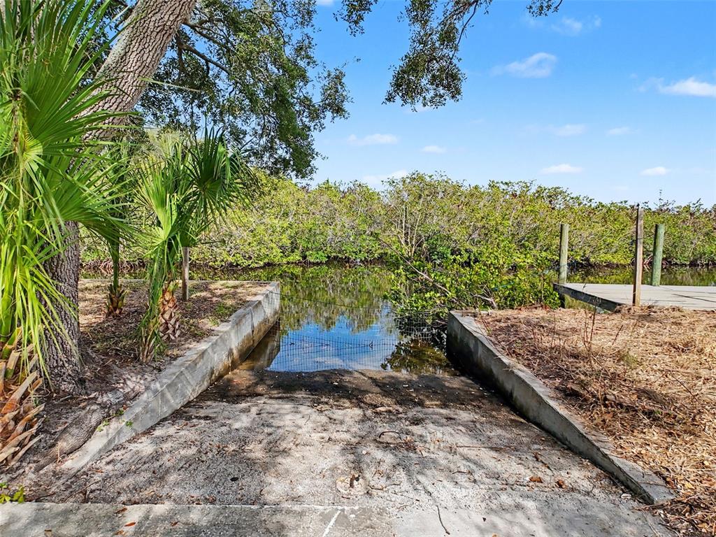 A concrete boat ramp leads into a small, calm waterway surrounded by dense green mangroves — LOT 8 RICE ROAD, HUDSON, FL