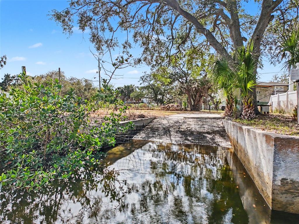A concrete boat ramp leads into a shallow, calm body of water under large trees — LOT 8 RICE ROAD, HUDSON, FL