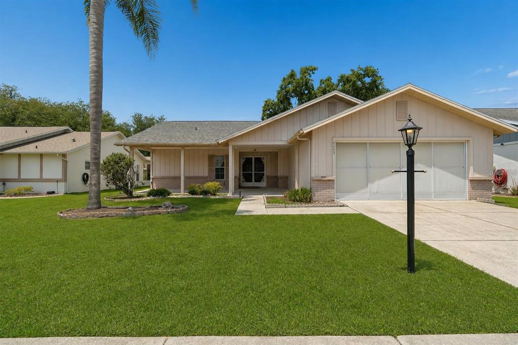 A single-story house with beige siding, a two-car garage, and a front lawn — 4643 SANDPOINTE DRIVE, NEW PORT RICHEY, FL