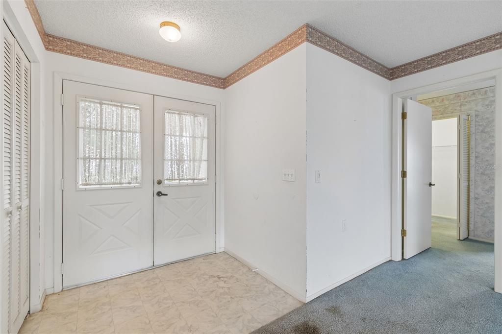 An entryway with white double doors, a tiled floor, and a doorway leading to a closet — 4643 SANDPOINTE DRIVE, NEW PORT RICHEY, FL