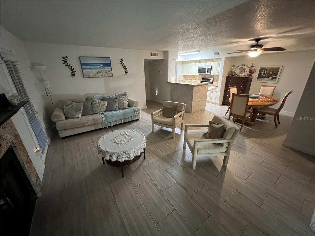 A living room and dining area with tile flooring, a sofa, and two armchairs — 5587 DEVONBRIAR WAY UNIT J105, ORLANDO, FL