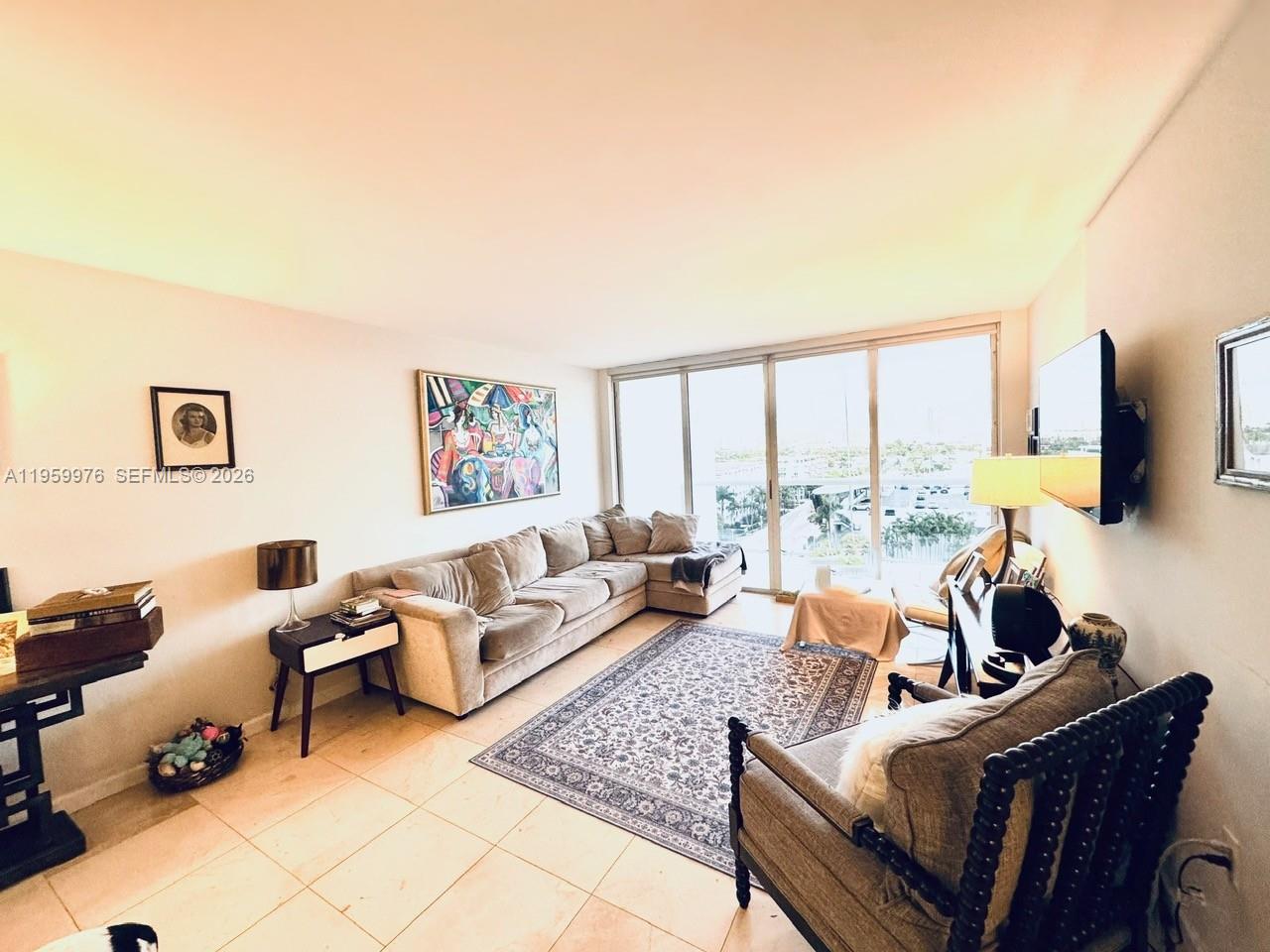 A living room features a sectional sofa, patterned area rug, and floor-to-ceiling windows with views — 1900 Sunset Harbour Dr # 1009, Miami Beach FL 33139, MIAMI BEACH, FL