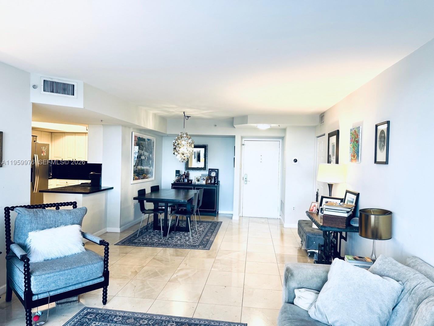 This open-concept living and dining area features tile flooring, a modern chandelier, and neutral walls — 1900 Sunset Harbour Dr # 1009, Miami Beach FL 33139, MIAMI BEACH, FL