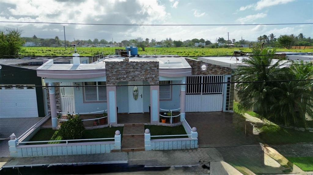 An exterior view of a single-story house with a stone-accented entrance and a front yard — A11 BO ISLOTE, COSTA ATLANTICO, ARECIBO, PR