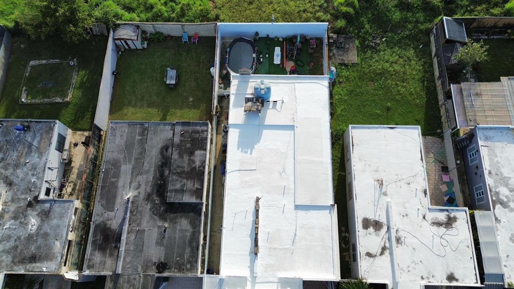 An aerial view shows a white-roofed house flanked by neighboring properties with yards and pools — A11 BO ISLOTE, COSTA ATLANTICO, ARECIBO, PR