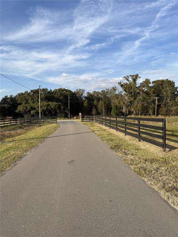 A paved driveway leads toward a stop sign between two black wooden fences — 14950 MIM PLACE, DADE CITY, FL