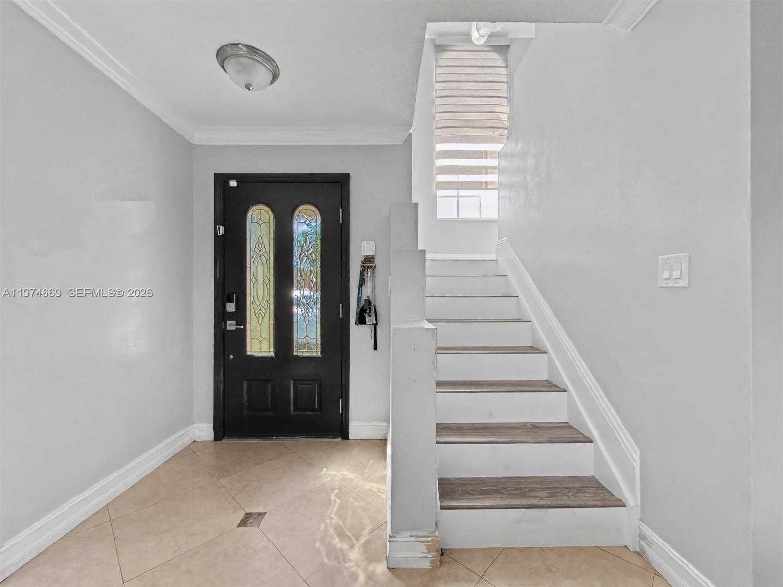 An entryway features a black front door, tiled floor, and a staircase with wood treads — 12689 NW 10th Way, Miami FL 33182, MIAMI, FL