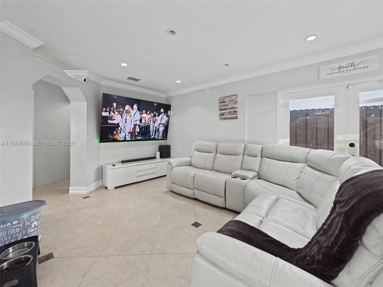 A living room features a large sectional sofa, a wall-mounted television, and tile flooring — 12689 NW 10th Way, Miami FL 33182, MIAMI, FL