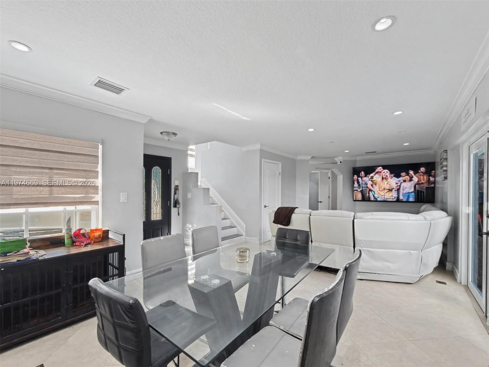 A dining area with a glass table and chairs sits before a living room space — 12689 NW 10th Way, Miami FL 33182, MIAMI, FL