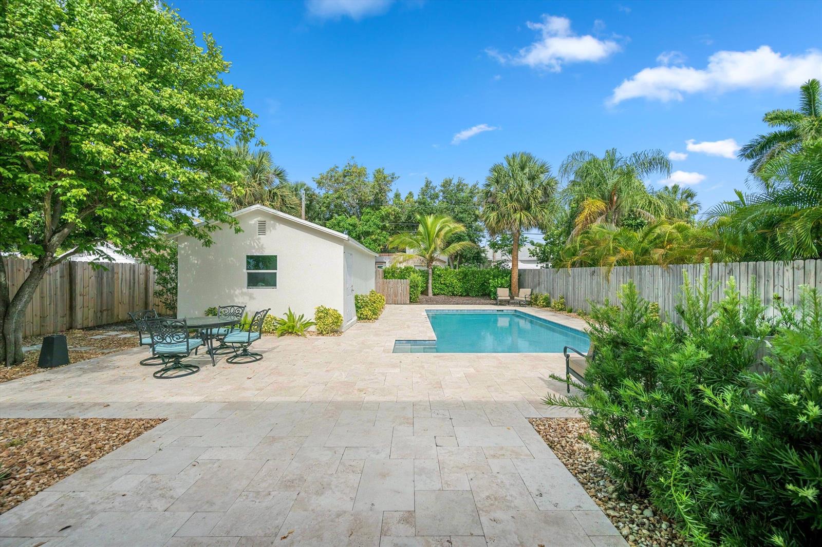 A backyard features a swimming pool, a patio with dining furniture, and a small building — 611 N Palmway, FL 33460, FL
