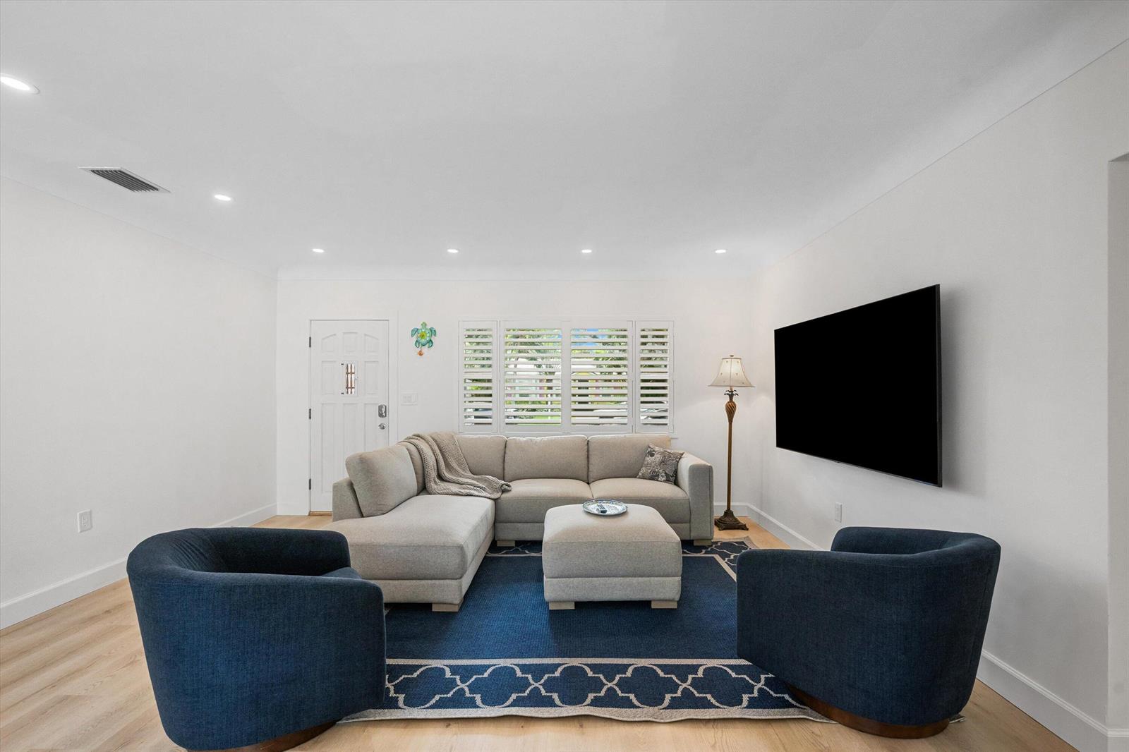 A living room features a sectional sofa, two blue armchairs, and a wall-mounted television — 611 N Palmway, FL 33460, FL