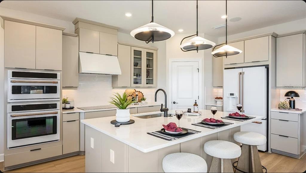 A modern kitchen features light-toned cabinetry, a central island with bar seating, and white appliances — 14224 DUNLIN AVENUE, PUNTA GORDA, FL