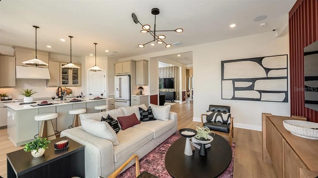 A modern open-concept living room and kitchen featuring a sofa, island, and contemporary light fixtures — 14224 DUNLIN AVENUE, PUNTA GORDA, FL