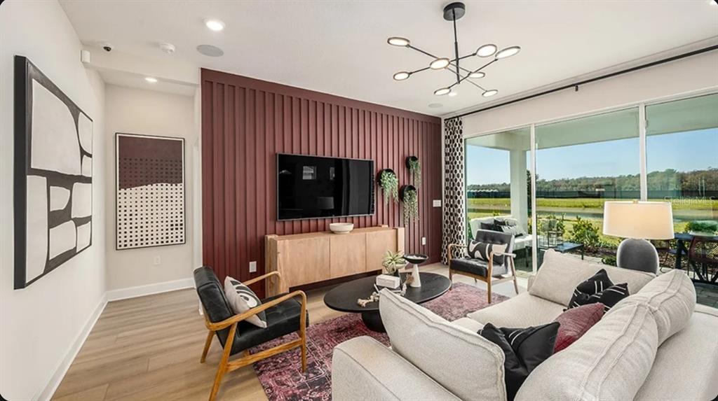 A living room features a dark red slatted accent wall, a television, and large windows — 14224 DUNLIN AVENUE, PUNTA GORDA, FL