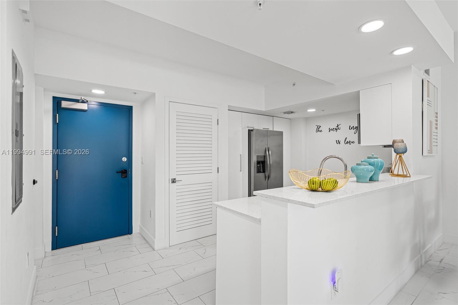 A kitchen with white cabinetry, stainless steel appliances, and a blue door in the entryway — 1850 Monroe St # 205, Hollywood FL 33020, HOLLYWOOD, FL