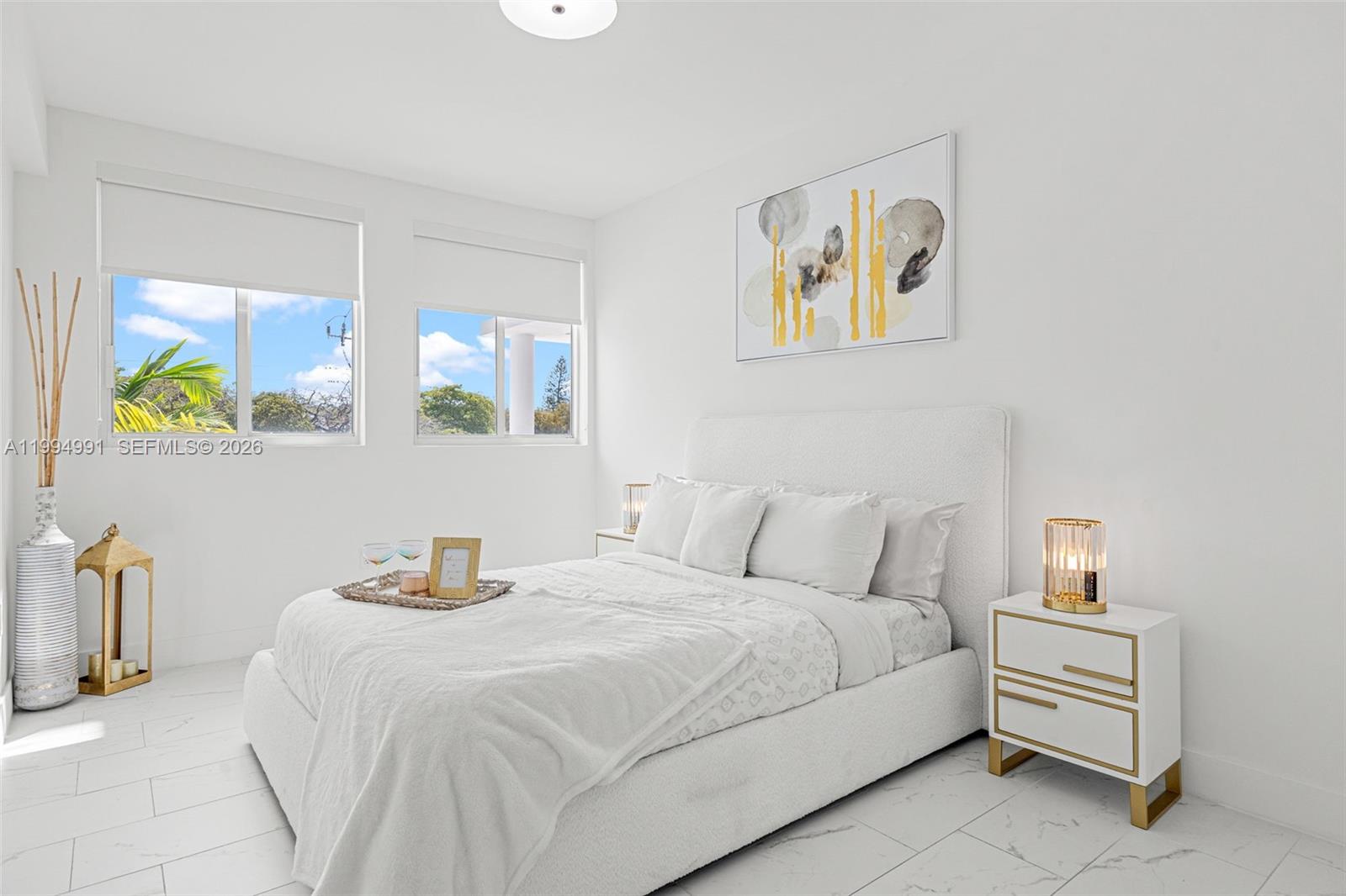 A bright bedroom features a white upholstered bed, marble-style flooring, and two windows — 1850 Monroe St # 205, Hollywood FL 33020, HOLLYWOOD, FL