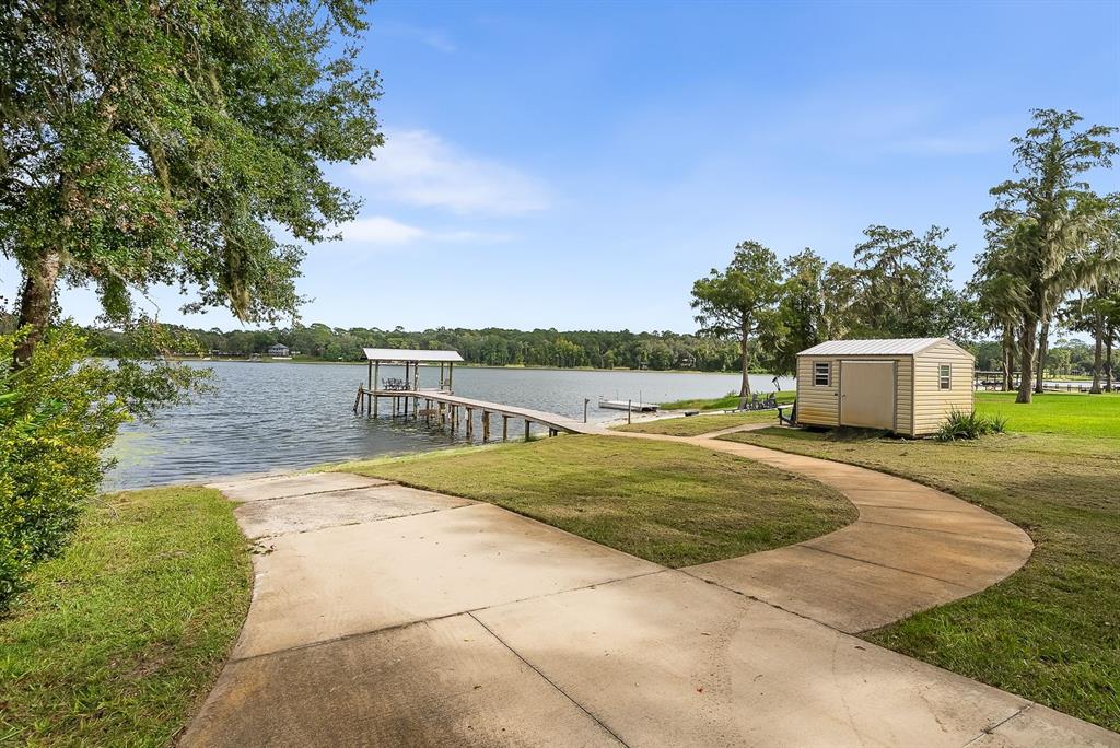A concrete boat ramp leads to a wooden dock and a shed on a lake — 8449 LILLY LAKE ROAD, MELROSE, FL